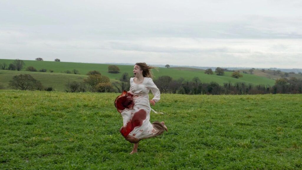 Cecilia (Sydney Sweeney) court avec une robe ensanglantée dans le film Immaculée